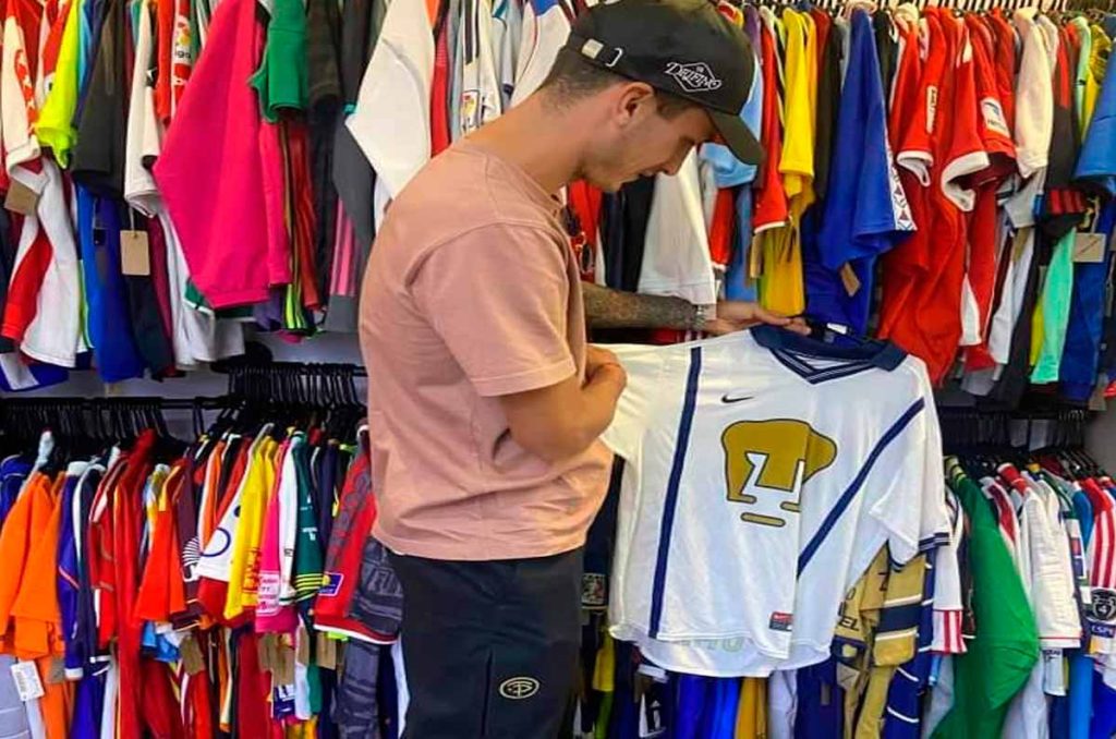 Juan Ignacio Dinenno sosteniendo un jersey retro de Pumas en la tienda El Jugador Número 12