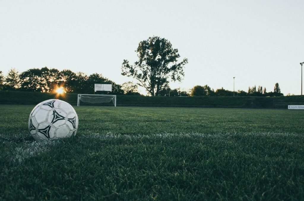 Balón en medio de una cancha de fútbol con vista al atardecer